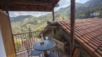Un balcón con una mesa y sillas, con vistas a un paisaje montañoso.