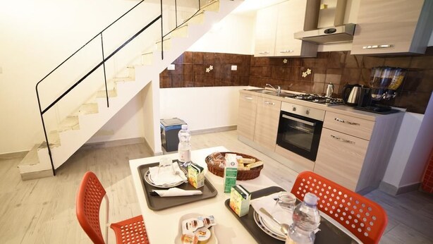 Una cocina moderna con comedor, que incluye una escalera, armarios de madera y una zona para desayunar.