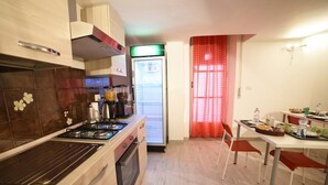 Una cocina moderna con estufa, horno y refrigerador. Hay un comedor con mesa y sillas.