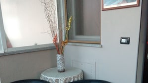 A corner seating area with two black leather chairs, a small round table with a floral vase, and a framed picture of a seascape on the wall. - Hotel Niagara (Caselle Torinese)