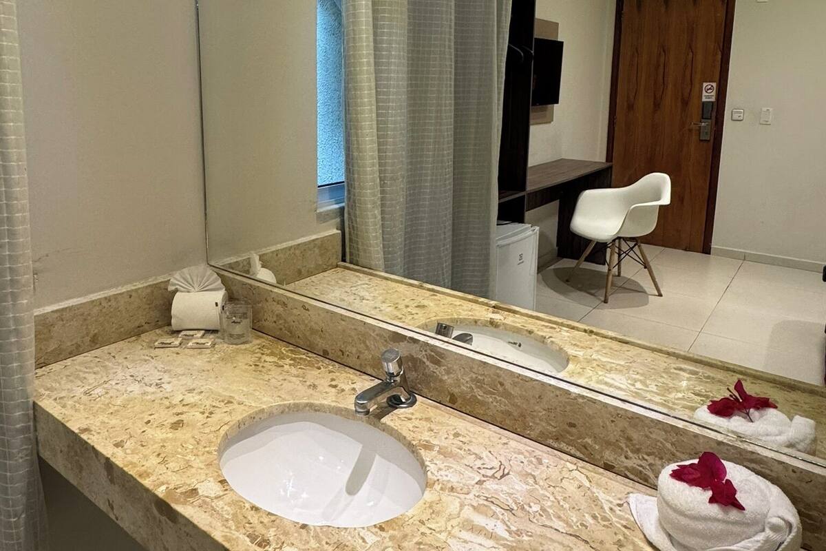 A bathroom with a marble countertop, a sink, a mirror, and a shower curtain.