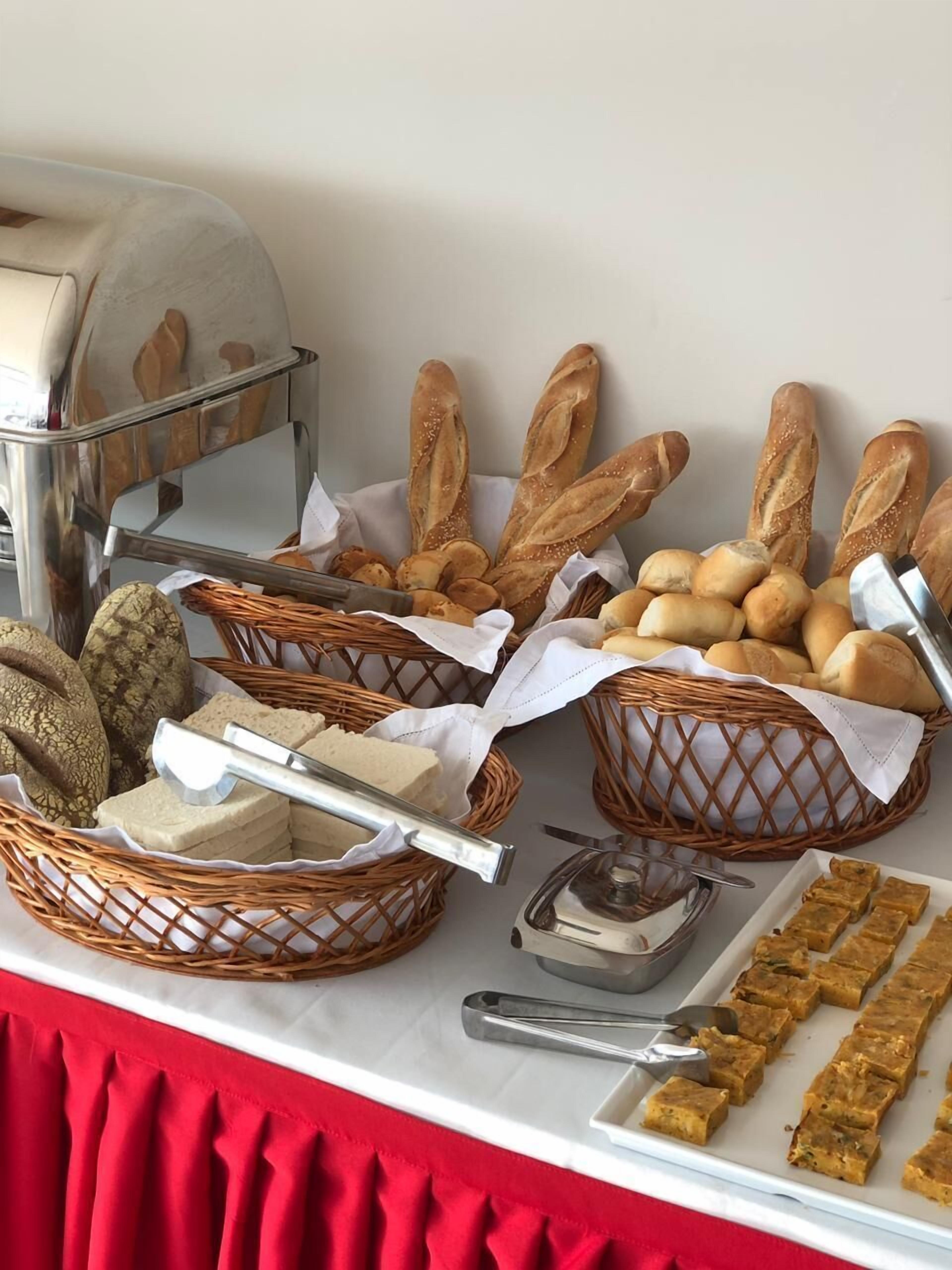 Une table de buffet proposant divers pains, fromages et un plat de viande.