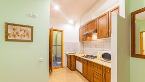 A compact kitchen with wooden cabinets, a gas stove, a microwave, and a tiled backsplash. - Apartment Sea and City Center (Odesa)