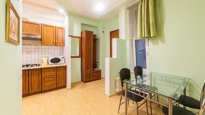 A compact kitchen with wooden cabinets, a microwave, and a glass dining table with chairs. - Apartment Sea and City Center (Odesa)