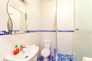 A bathroom with a white sink, a toilet, and a shower with blue-tiled flooring. - Apartment Sea and City Center (Odesa)