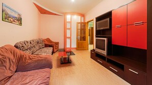 A living room with a sofa, a TV, and red cabinets. - Apartment Sea and City Center (Odesa)