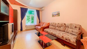 A living room with a sofa, a glass coffee table, a TV, and a window with curtains. - Apartment Sea and City Center (Odesa)