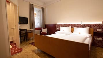 A hotel room with a large bed, a desk, and a television.