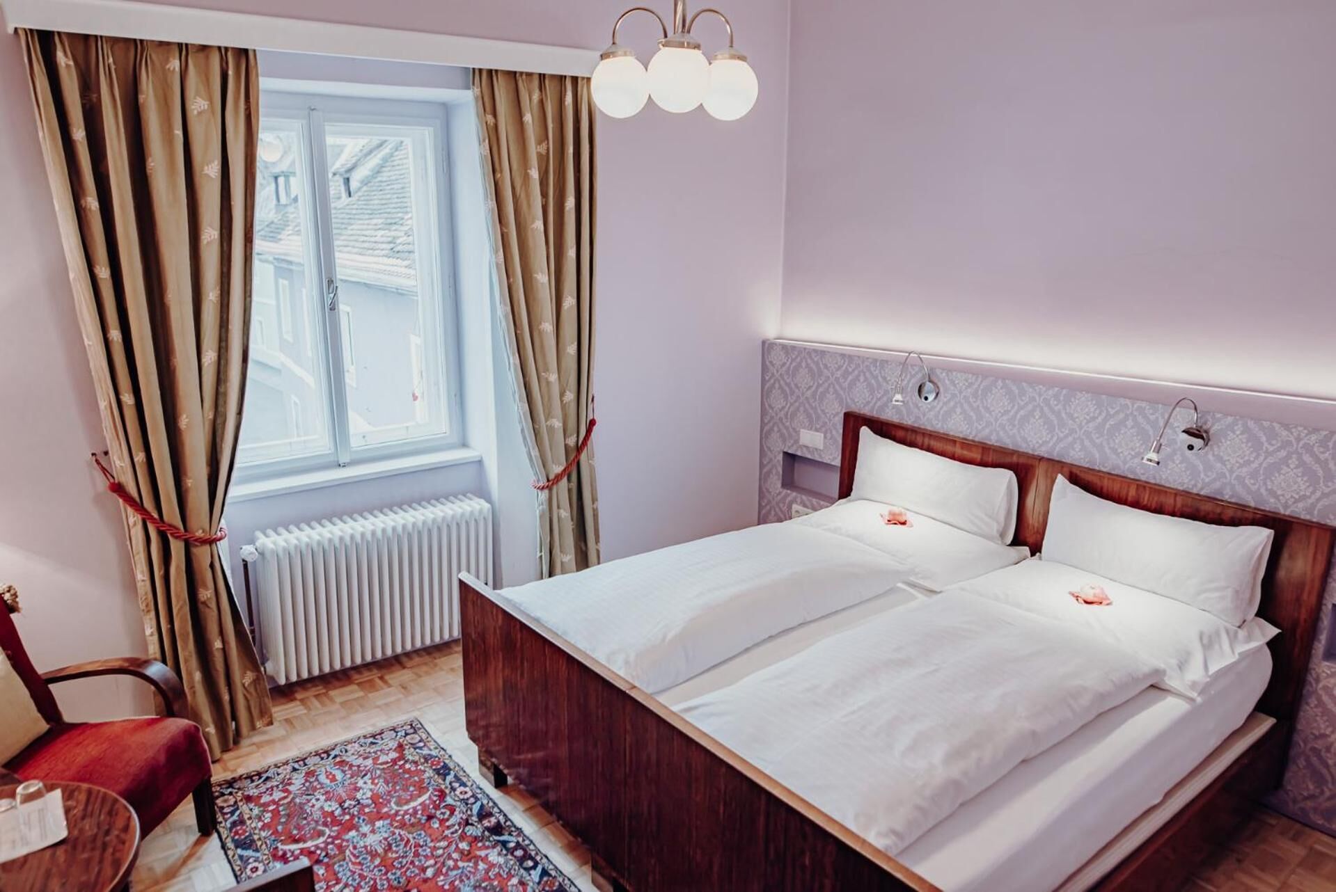 Een tweepersoonsbed met witte lakens, een houten hoofdbord en een nachtkastje met een lamp.