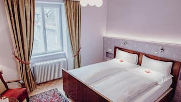 Een tweepersoonsbed met witte lakens, een houten hoofdbord en een nachtkastje met een lamp.