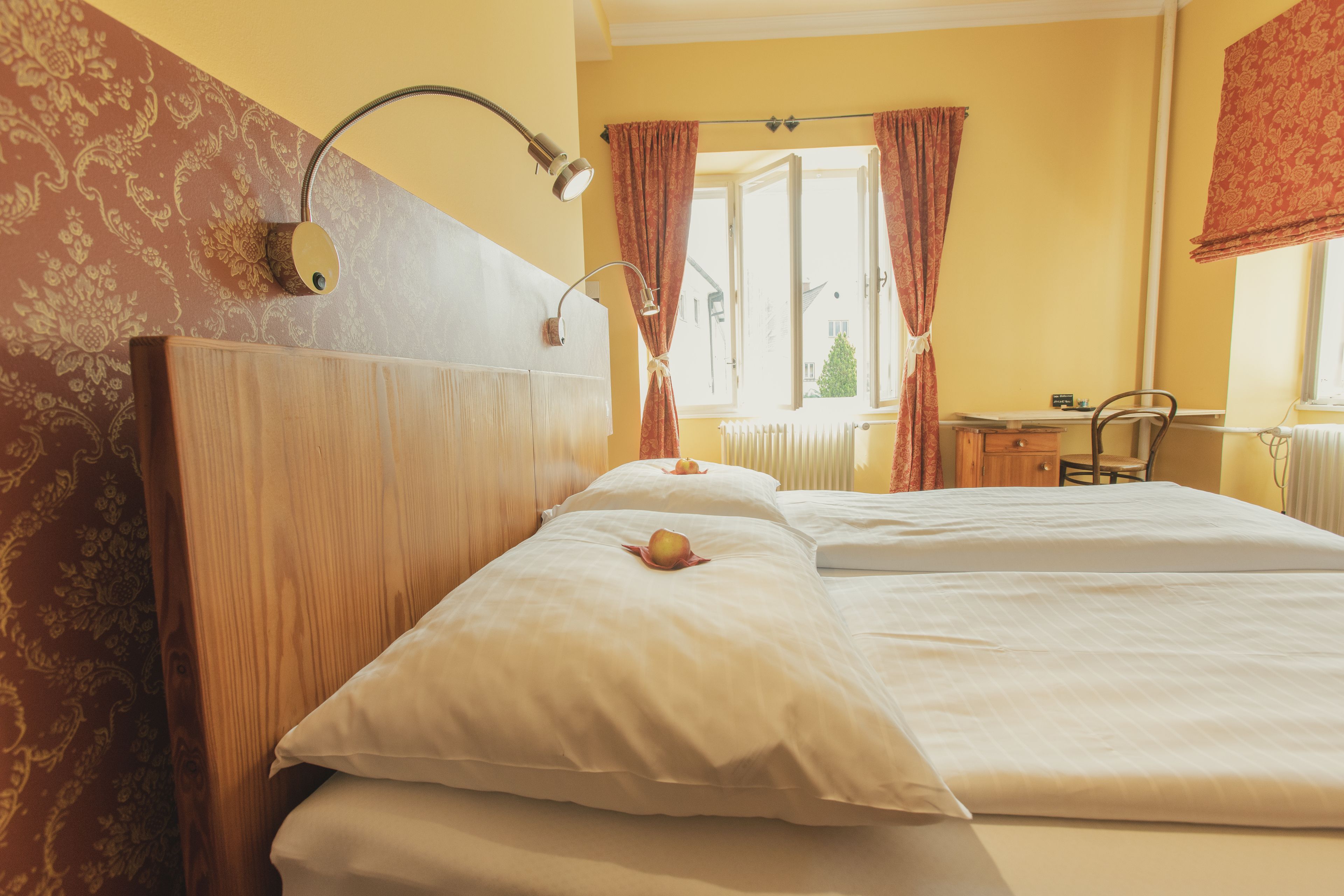 Camera d'albergo con due letti, una scrivania e una sedia.