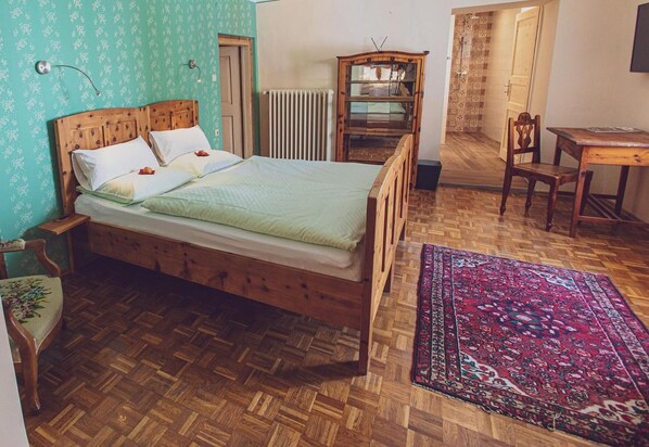 A room with a wooden bed, a wooden desk, a chair, a radiator, and a patterned rug. - Gasthof Eberhard (Sankt Michael in Obersteiermark)