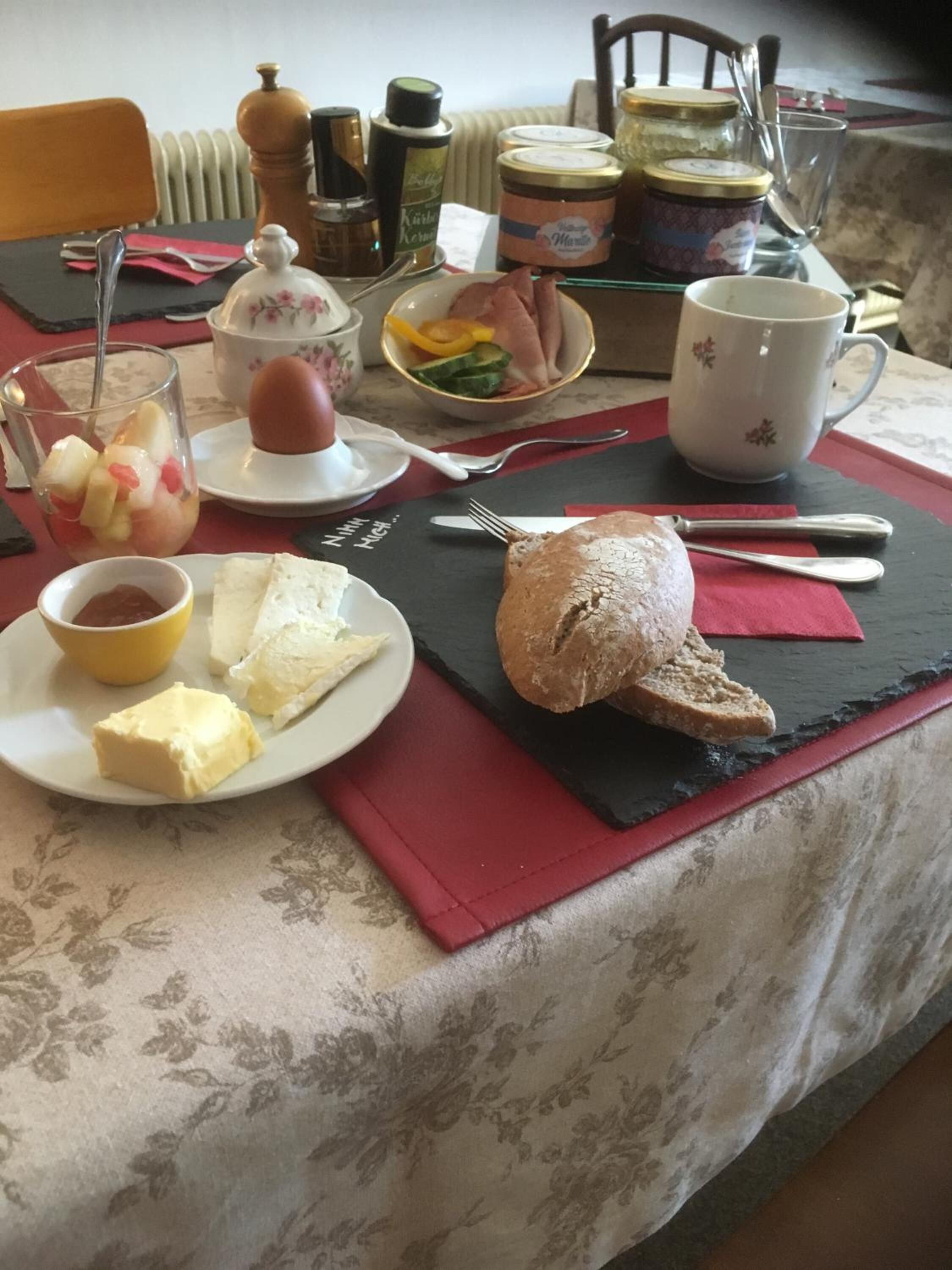 A breakfast setting with a plate of toast, butter, jam, and a glass of fruit.