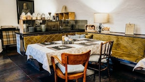A dining area with a table set for two, a wooden bench, and a wall-mounted menu board.