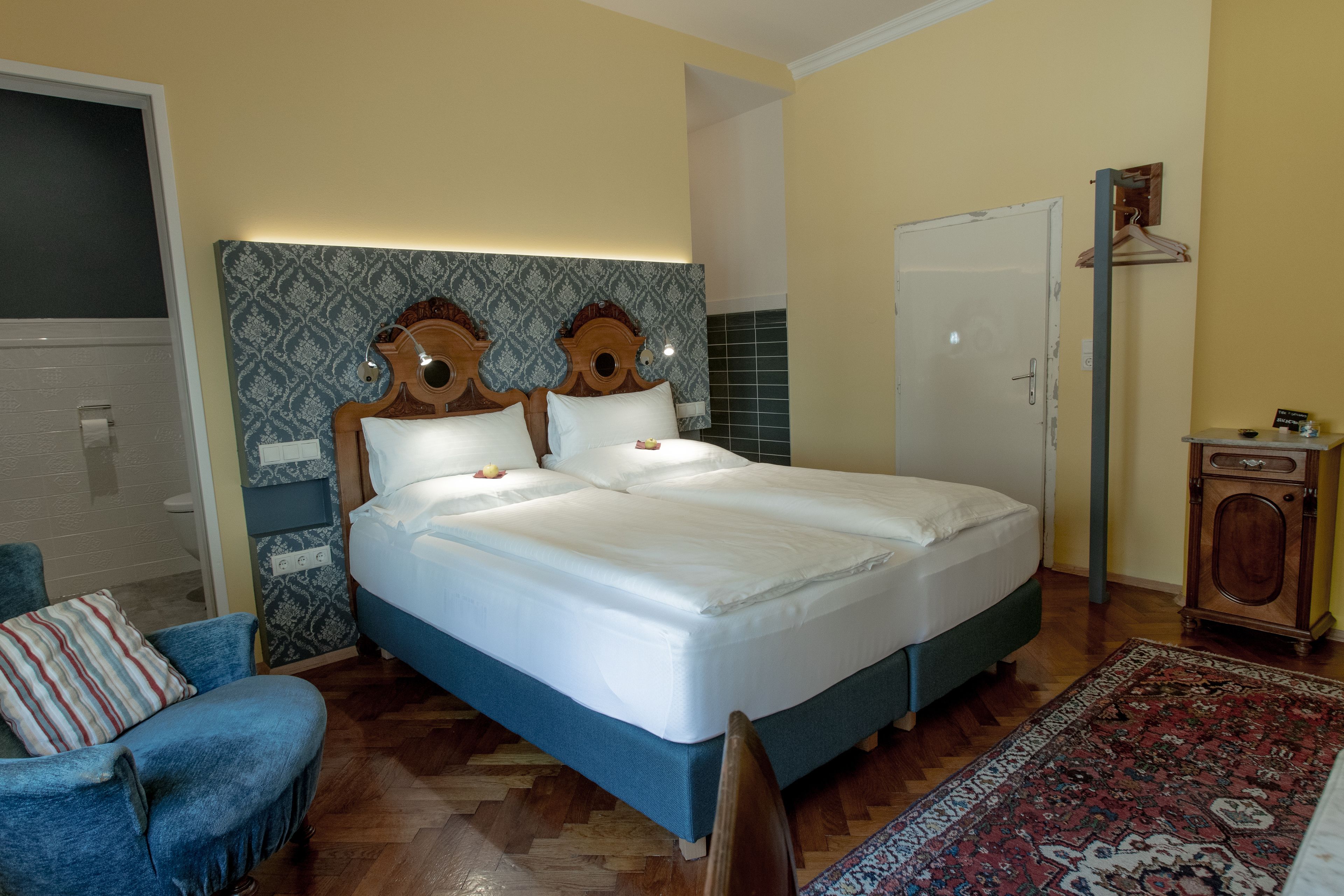 Ein Schlafzimmer mit einem großen Bett, einem Sessel, einem Kleiderschrank und einer Tür.