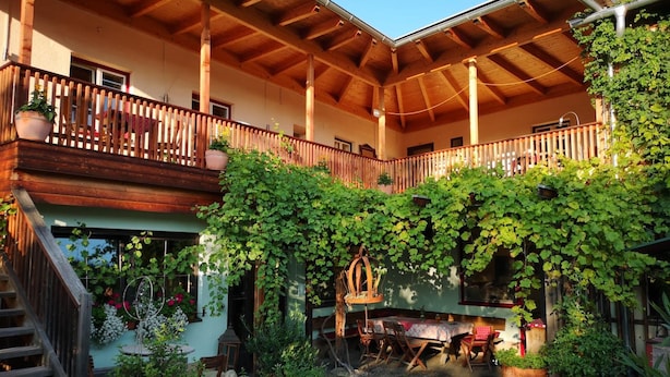 A covered outdoor dining area with wooden beams and a balcony with a wooden railing.