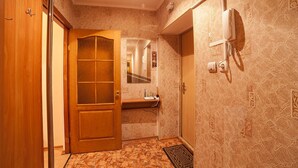 A hotel room with a wooden door, a small desk with a mirror, a telephone, and patterned wallpaper. - Apartment City Center Osipova 4 (Odesa)