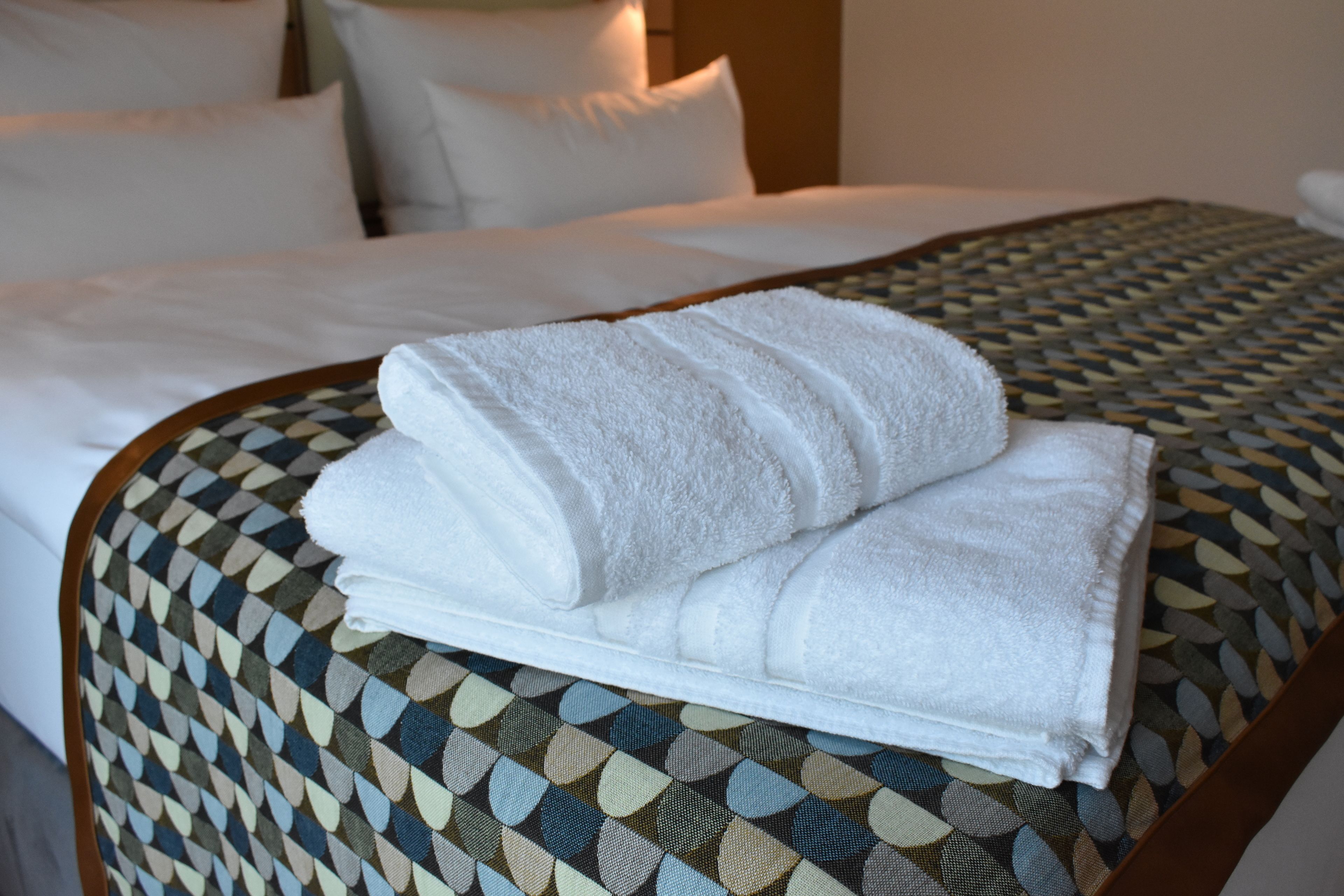 Una cama bien tendida con sábanas blancas y una colcha estampada.
