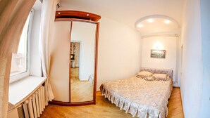 A bedroom with a bed, a mirror, a radiator, and a picture on the wall. - Balcony Apartment near Deribasovskaya (Odesa)