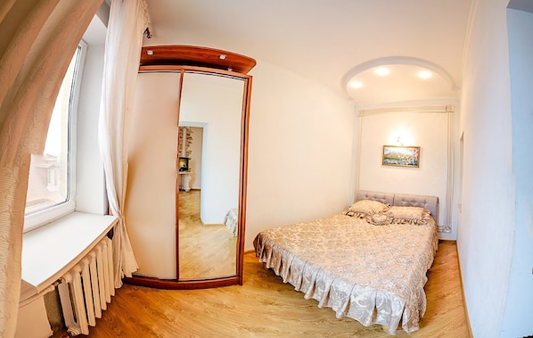 A bedroom with a bed, a mirror, a radiator, and a picture on the wall.
