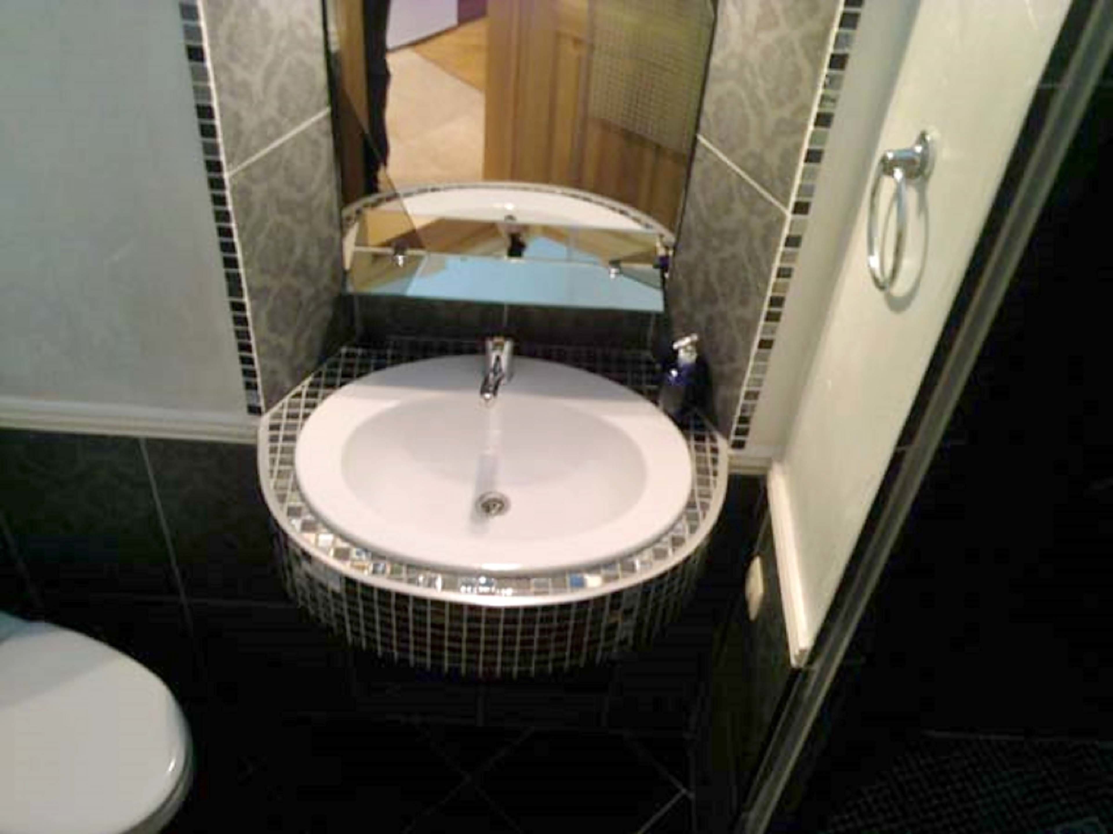 Un baño con lavabo redondo, inodoro y zona de ducha.
