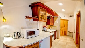 A kitchen with a microwave, kettle, and wooden cabinets. - Balcony Apartment near Deribasovskaya (Odesa)