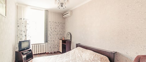 Un dormitorio con cama, televisor, cómoda y silla.