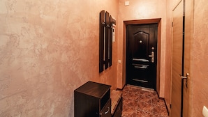 Um corredor com paredes texturizadas, uma porta com puxador e um pequeno armário de madeira.