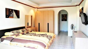 A bedroom with a large bed, a wardrobe, a TV, and a ceiling fan. - Sea Views With Rentbuythailand (Pattaya)