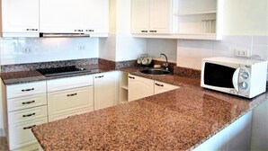 A kitchen with white cabinets, granite countertops, a built-in microwave, and a sink. - Sea Views With Rentbuythailand (Pattaya)
