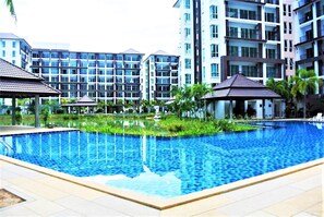 A swimming pool surrounded by modern buildings with multiple balconies. - Bang Saray - Lake & Pool Views (Sattahip)