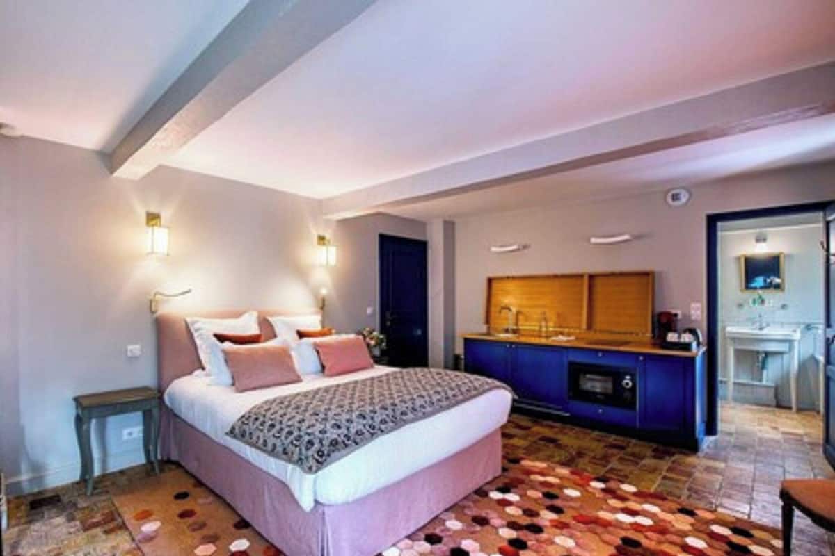 A bedroom with a bed, bedside tables, a dresser, a mirror, and a bathroom visible through an open door.