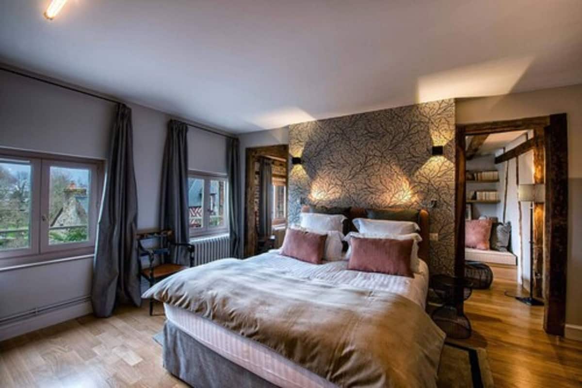 A bedroom with a large bed, a view of the outdoors through a window, and a patterned wall.
