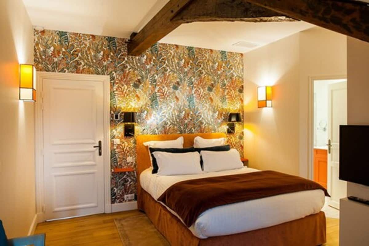 A bedroom with a bed, a door, and two wall-mounted lamps.