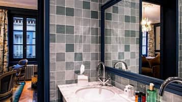 A modern bathroom with a large mirror, a marble sink, and a view of the city through the window.