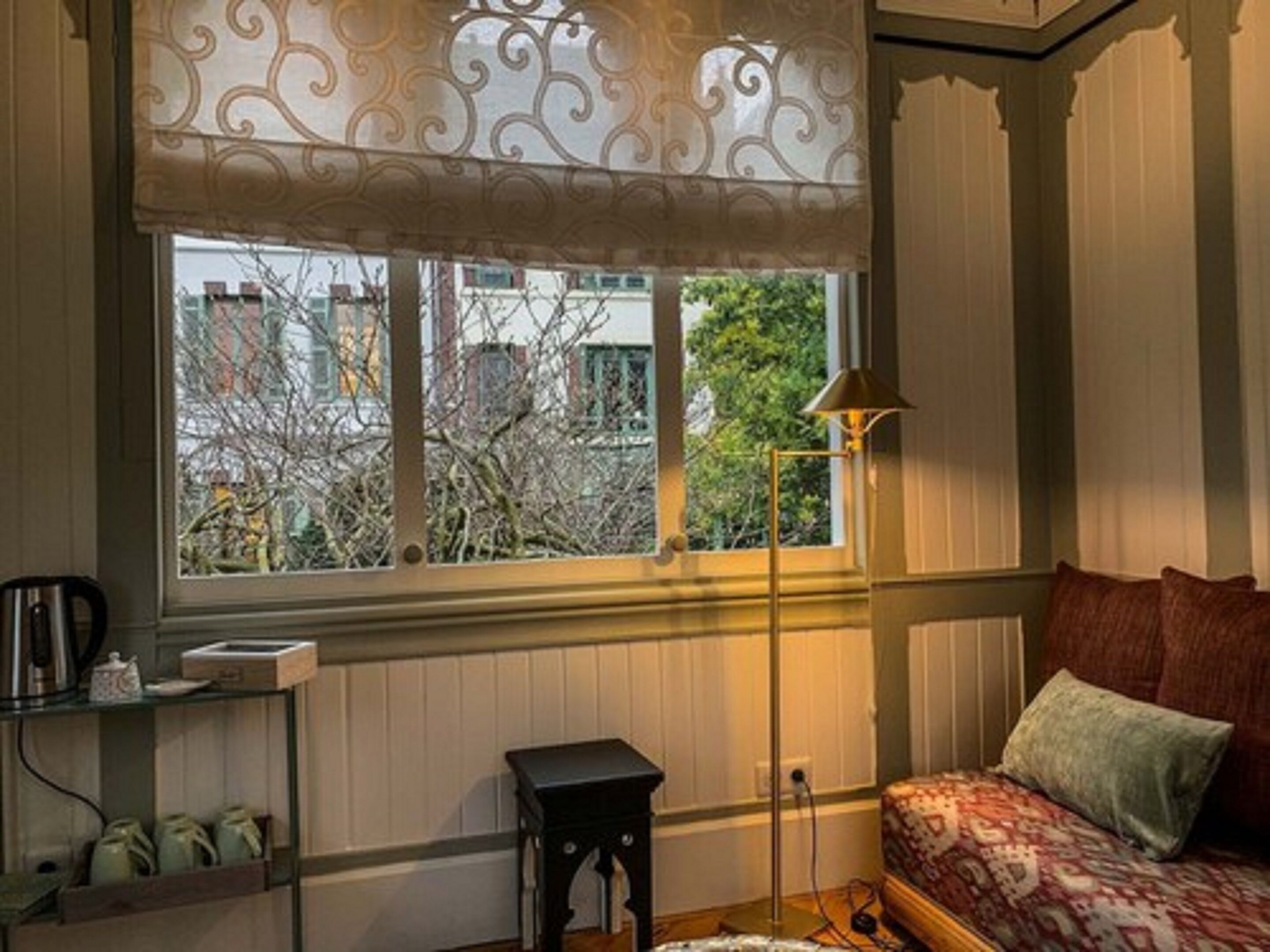 A bedroom with a window, a bedside table, a lamp, and a bed with pillows.