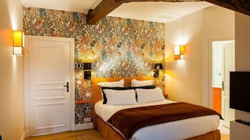 Un dormitorio con una cama, una puerta y una pared con estampado floral. Hay dos luces fijadas a la pared a ambos lados de la cama.