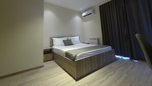 Een moderne hotelkamer met een groot bed, een nachtkastje, een airconditioner en een raam met gordijnen.