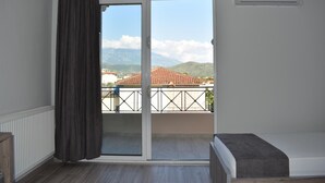 Een kamer met een schuifglasdeur die leidt naar een balkon, een bed, een radiator en een airconditioner.