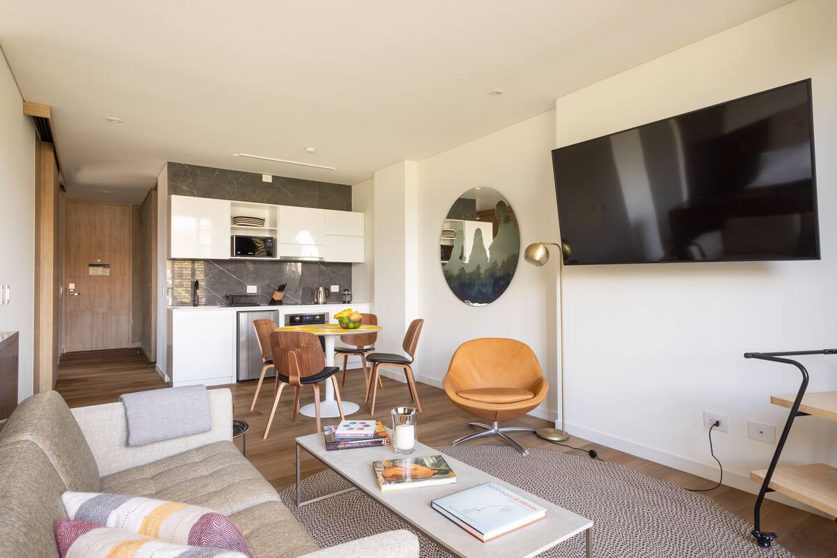 A modern living room with a sofa, coffee table, and a TV mounted on the wall.