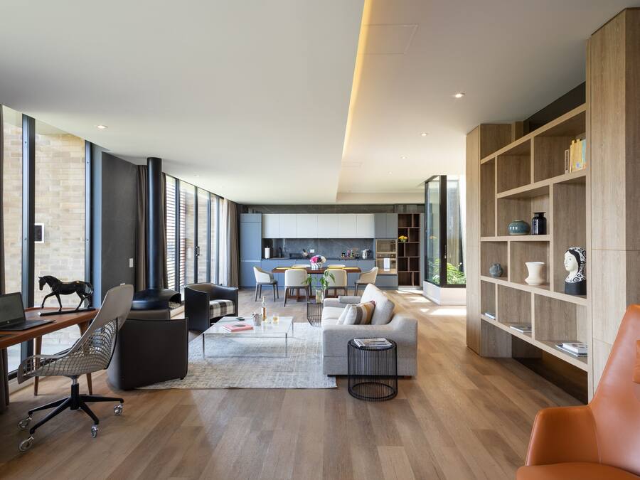Un salon moderne avec un canapé, une table basse et une bibliothèque. On aperçoit à l’arrière-plan un coin repas avec des chaises et une table.