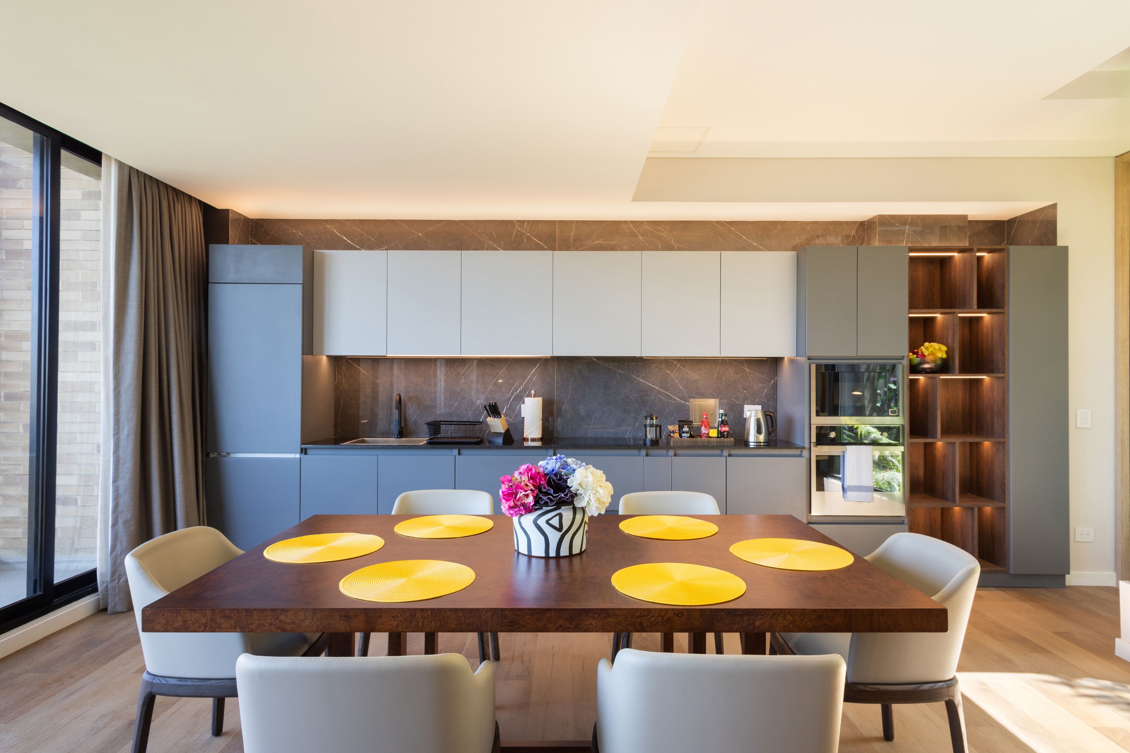 Un comedor moderno con una mesa de madera, seis sillas y un jarrón de flores.