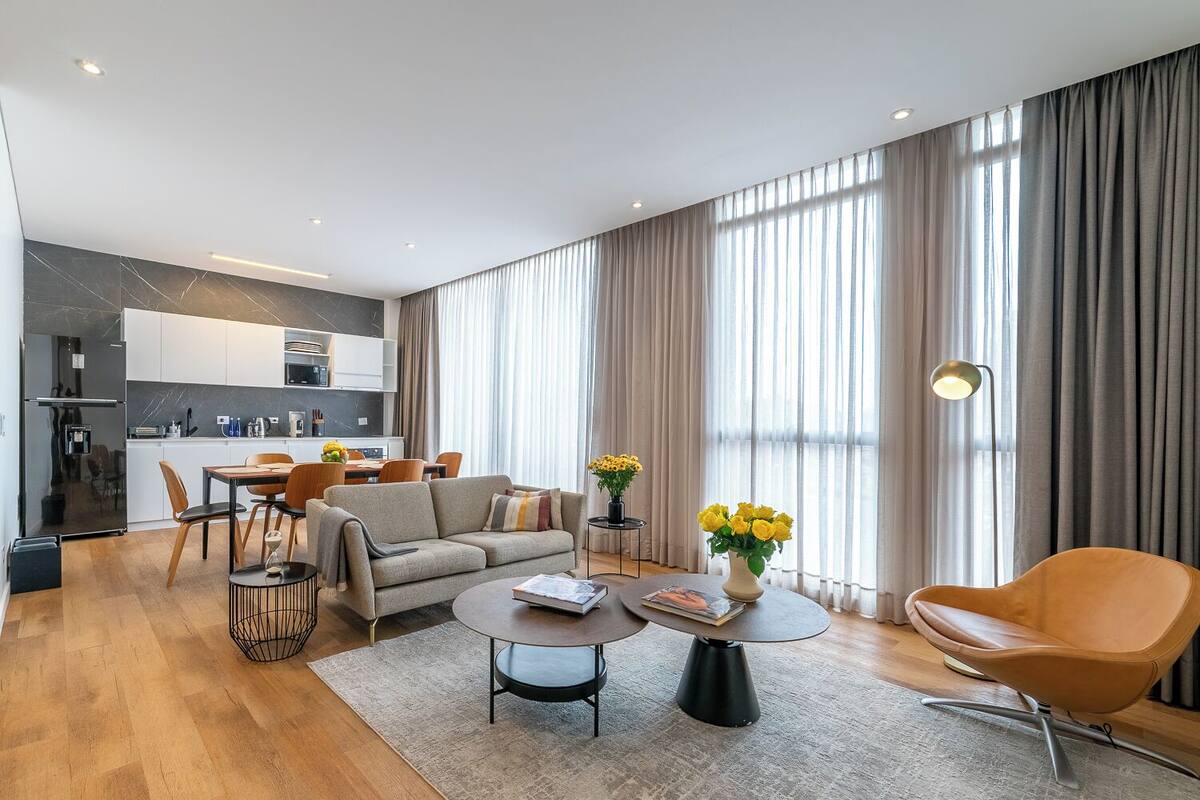 A modern living room with a sofa, coffee table, and a dining area with chairs.