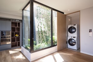 Une cuisine moderne dotée d’appareils électroménagers intégrés, d’une grande fenêtre donnant sur un espace verdoyant et d’un plancher en bois.