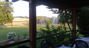 A covered outdoor seating area with tables and chairs, overlooking a grassy field and trees. - Agriturismo San Matteo (Tarquinia)