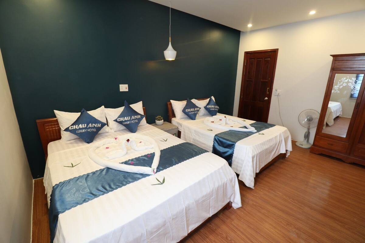 Ein Hotelzimmer mit zwei Betten, jeweils mit weißer Bettdecke und blauen Akzenten sowie passenden Kissen.