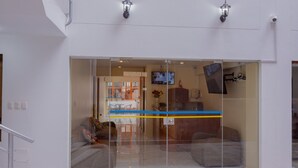 A modern interior with a glass door entrance, a staircase, and a seating area with a sofa and chairs. - Hawka Inka Hostal (Cusco)