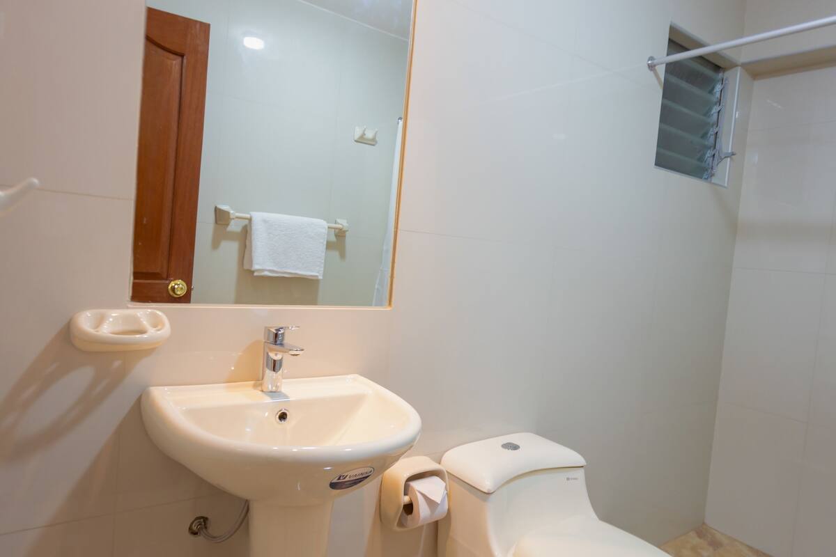 A bathroom with a pedestal sink, toilet, and a mirror above the sink.