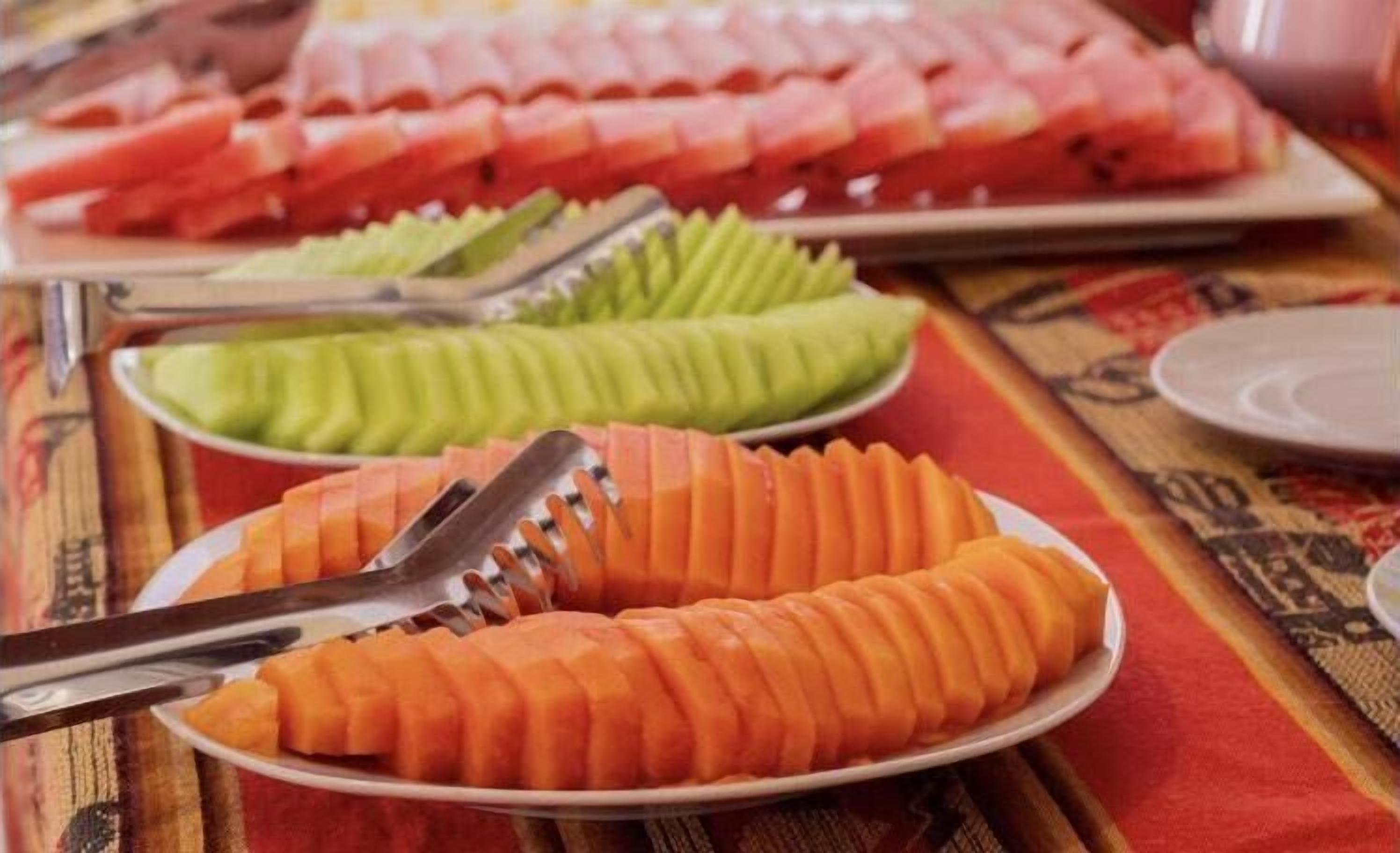 A table with neatly arranged food platters, including sliced fruits and vegetables.