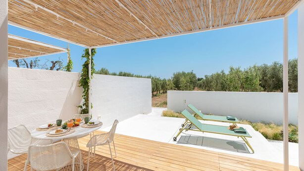 A patio with a table set for breakfast, a lounge chair, and a pergola. - Masseria Pensato SUITE CARRUBO (Fasano)